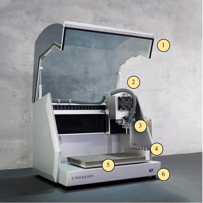 The Carvera with its protective cover open, showing the cover, vacuum hose, spindle, tool holder, MDF bed, and indicator light